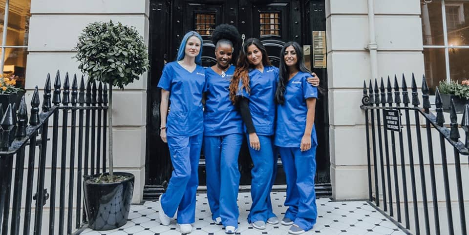 Four nurses in blue scrubs outside a Georgian clinic entrance at our Harley Street clinic, EMtone cellulite reduction London